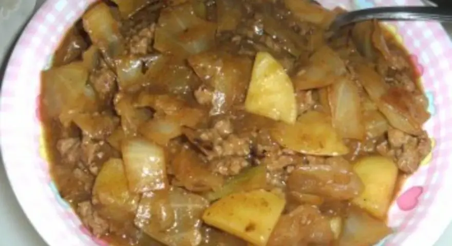 Herzhaftes Schichtkraut Rezept mit Hackfleisch und Kartoffeln in einer deftigen Sauce, serviert auf einem pink-weiß karierten Teller.