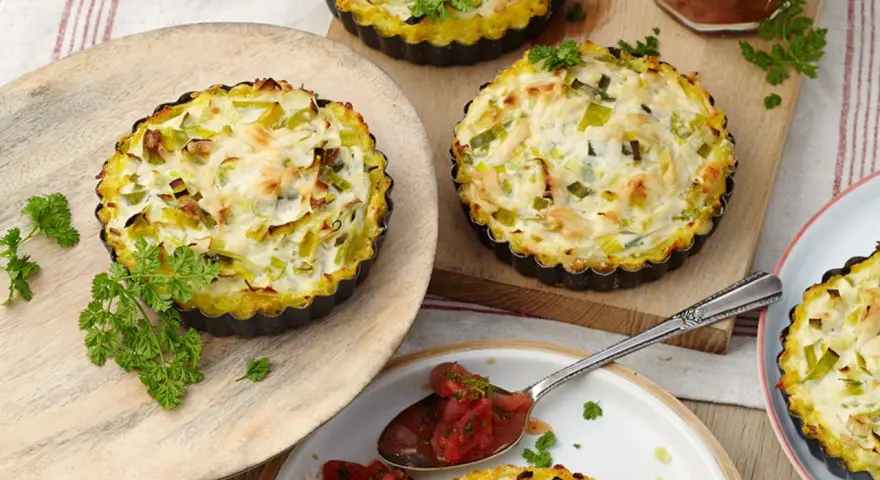 Kleine herzhafte Lauch-Tartelettes mit cremigem Belag, garniert mit Petersilie. Perfekt für Lauch Rezepte.