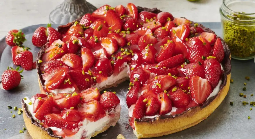 Saftiger Erdbeerkuchen mit frischen Erdbeeren, Sahne und gehackten Pistazien. Ein Traum für alle, die Rezepte mit Erdbeeren lieben!
