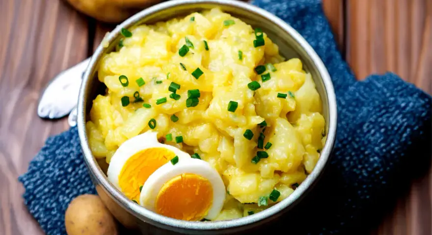 Omas Kartoffelsalat, cremig und mit Schnittlauch bestreut, serviert mit gekochten Eiern. Ein Klassiker, der immer schmeckt.