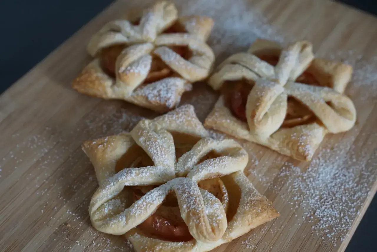 Drei goldbraune Apfeltaschen mit Puderzucker bestreut, bereit zum Genießen. Ein einfaches Apfeltaschen Rezept für süße Momente.