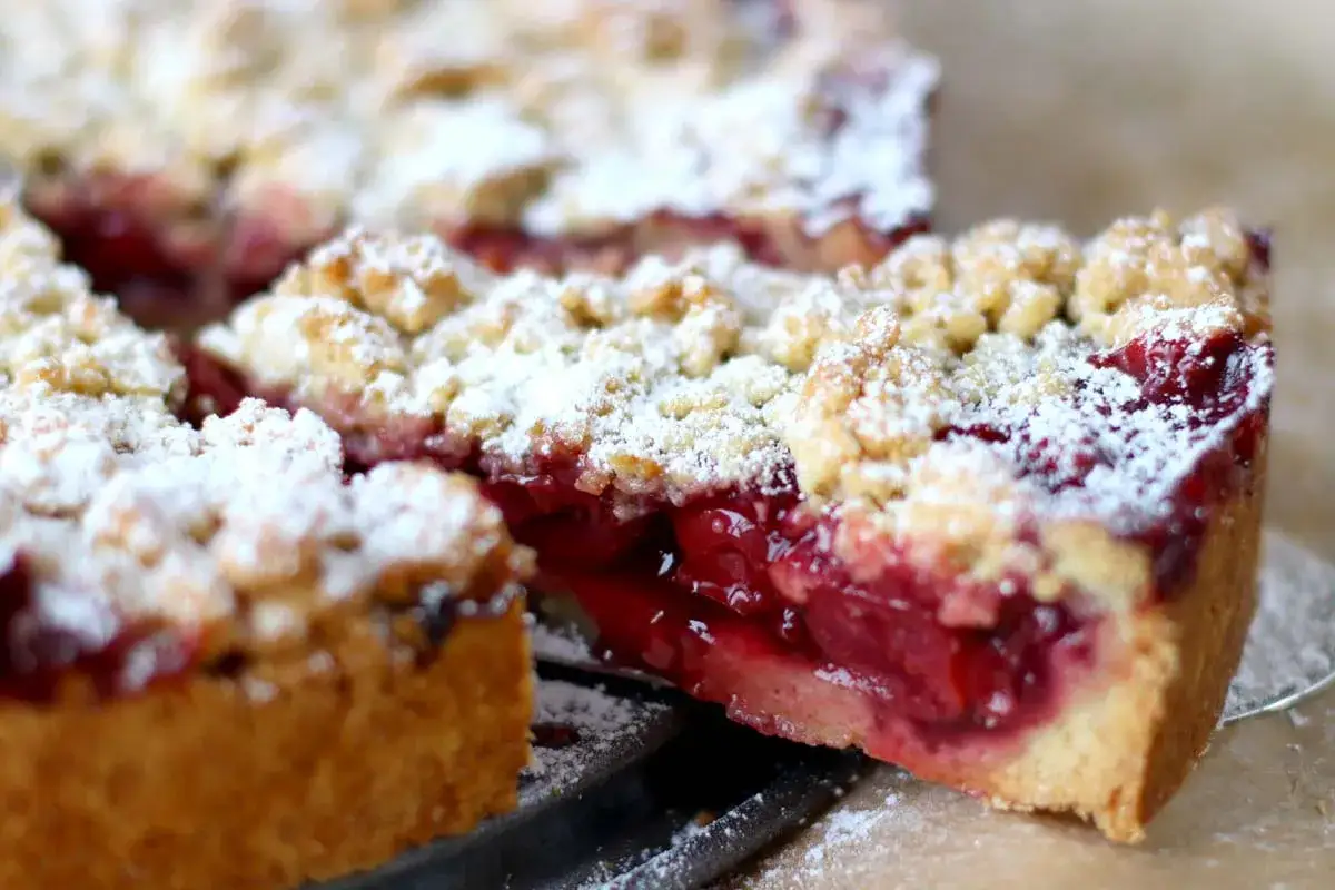 Ein saftiger Kirschstreuselkuchen, bestäubt mit Puderzucker, wartet darauf, genossen zu werden.