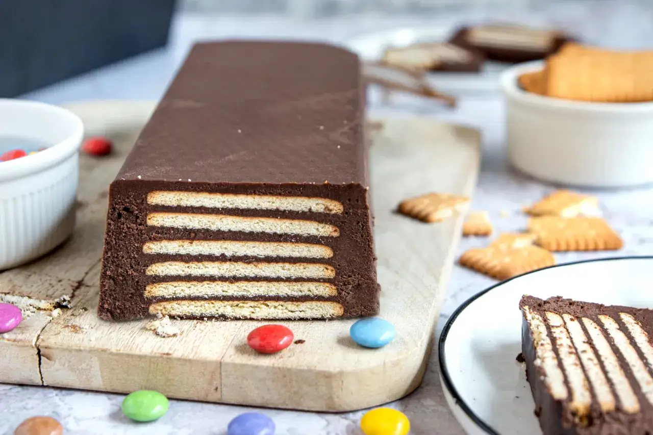 Schokoladiger Kalter Hund, Omas Rezept, geschichtet mit Keksen und überzogen mit dunkler Schokolade. Bunt dekoriert mit Schokolinsen.
