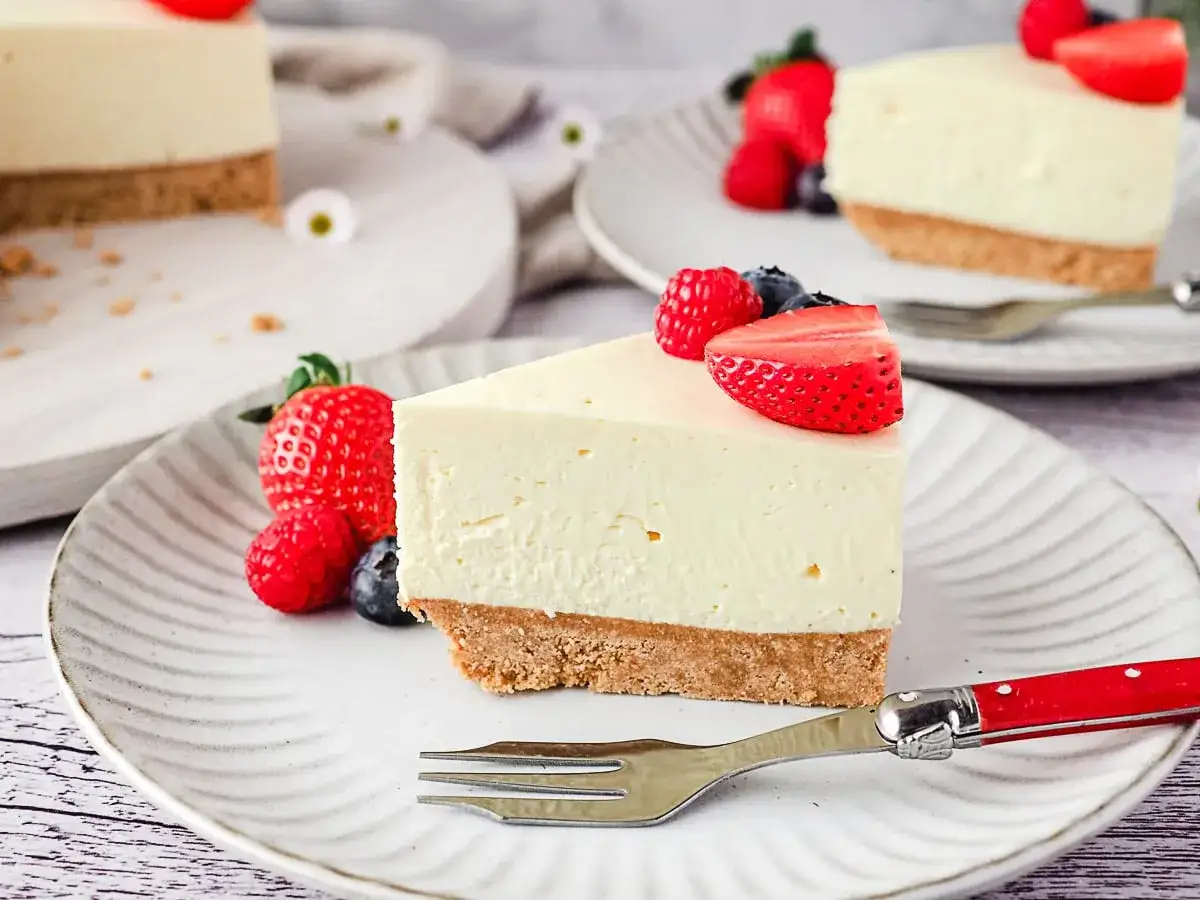 Ein cremiges Stück Philadelphia Torte mit frischen Beeren und einem knusprigen Boden.