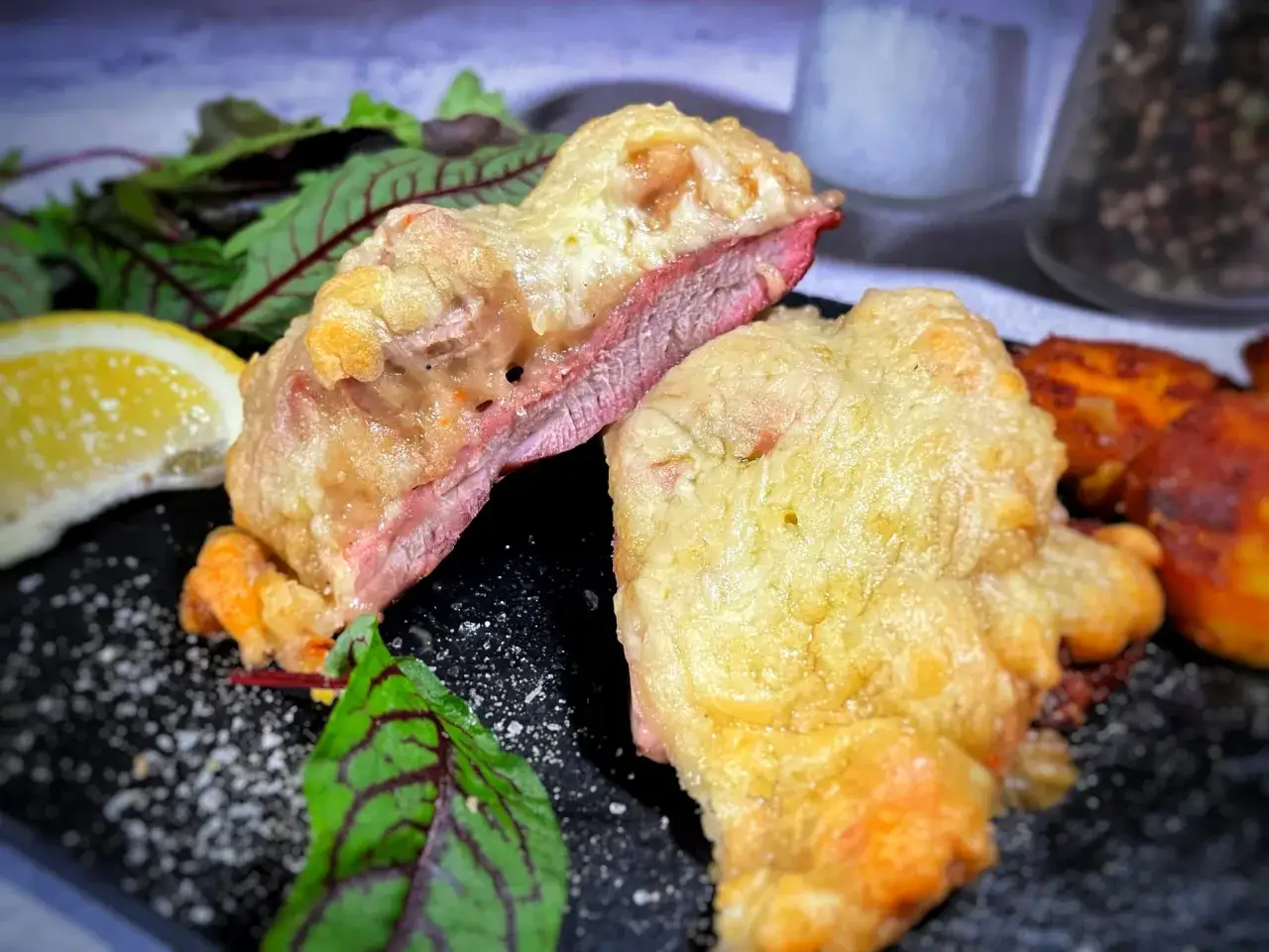 Zarte Scheiben eines Steak au Four mit knuspriger Kruste, serviert mit Salat und Zitronenspalte.
