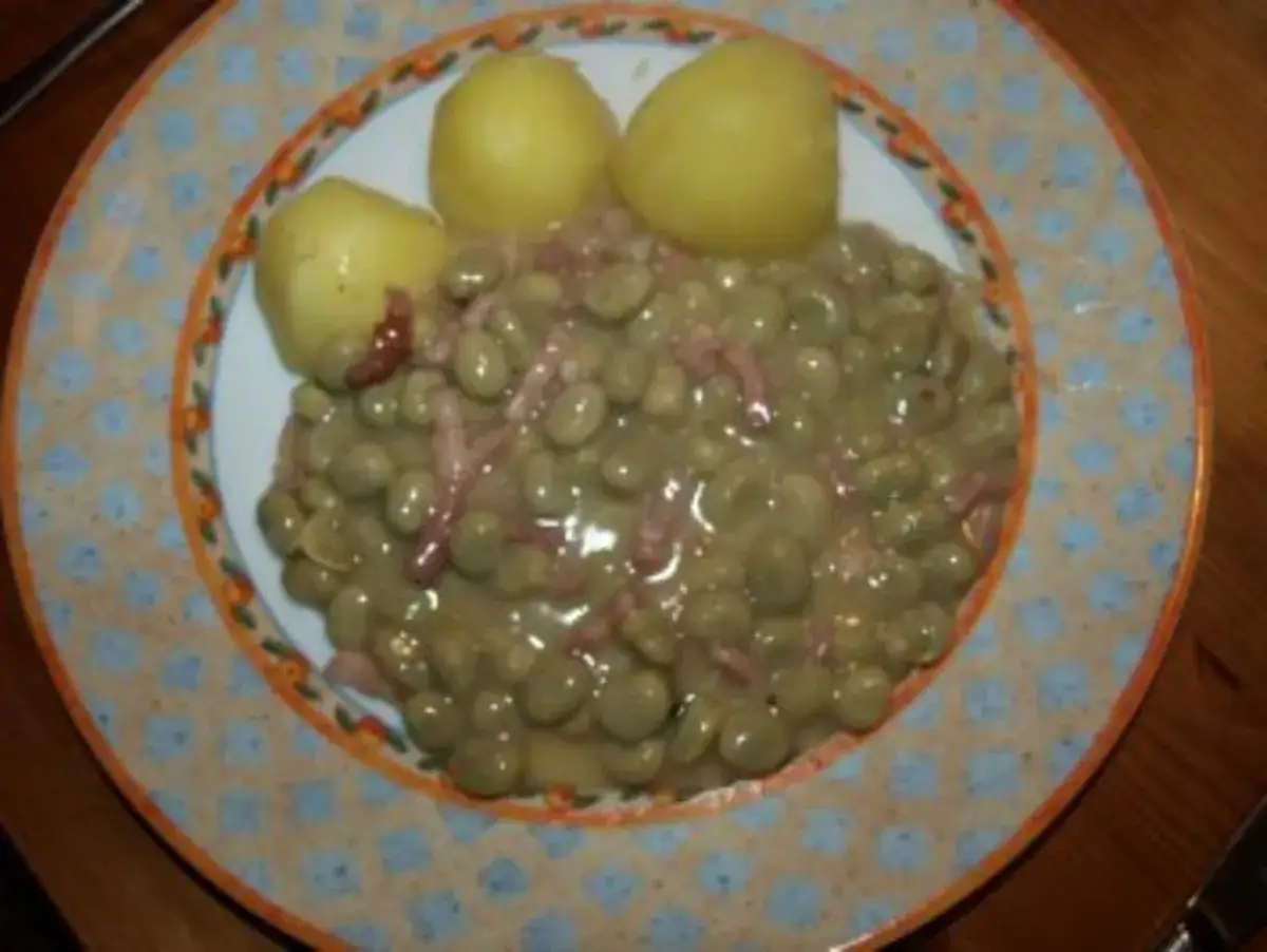 Omas dicke Bohnen mit Speck und Salzkartoffeln auf einem Teller mit buntem Rand.