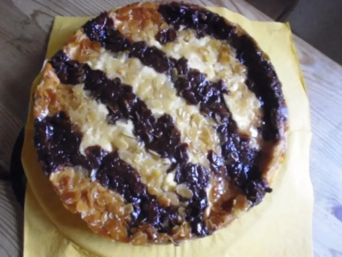 Ein runder Kuchen mit Schokoladen- und Mandelstreifen, perfekt für ein Hummelkuchen Rezept.