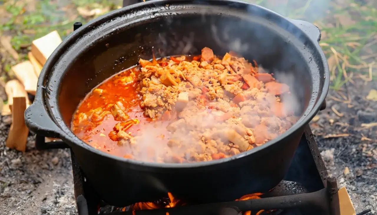 Ein dampfender Kessel mit herzhaftem Kesselgulasch, zubereitet über offenem Feuer. Das perfekte Rezept für ein rustikales Outdoor-Erlebnis.