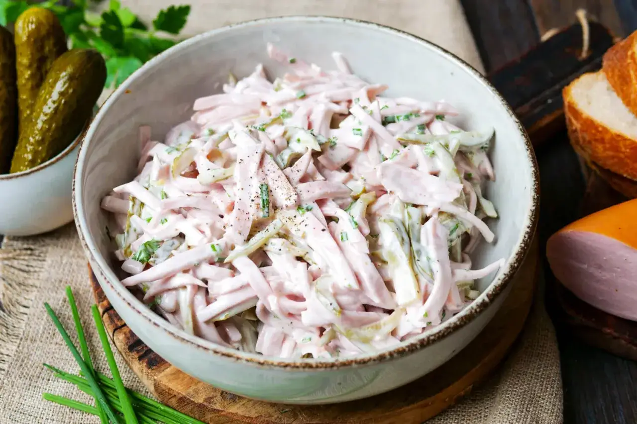 Schüssel mit cremigem Fleischsalat, garniert mit Schnittlauch. Dazu passen Gewürzgurken und frisches Brot – ein einfaches rezept fleischsalat.