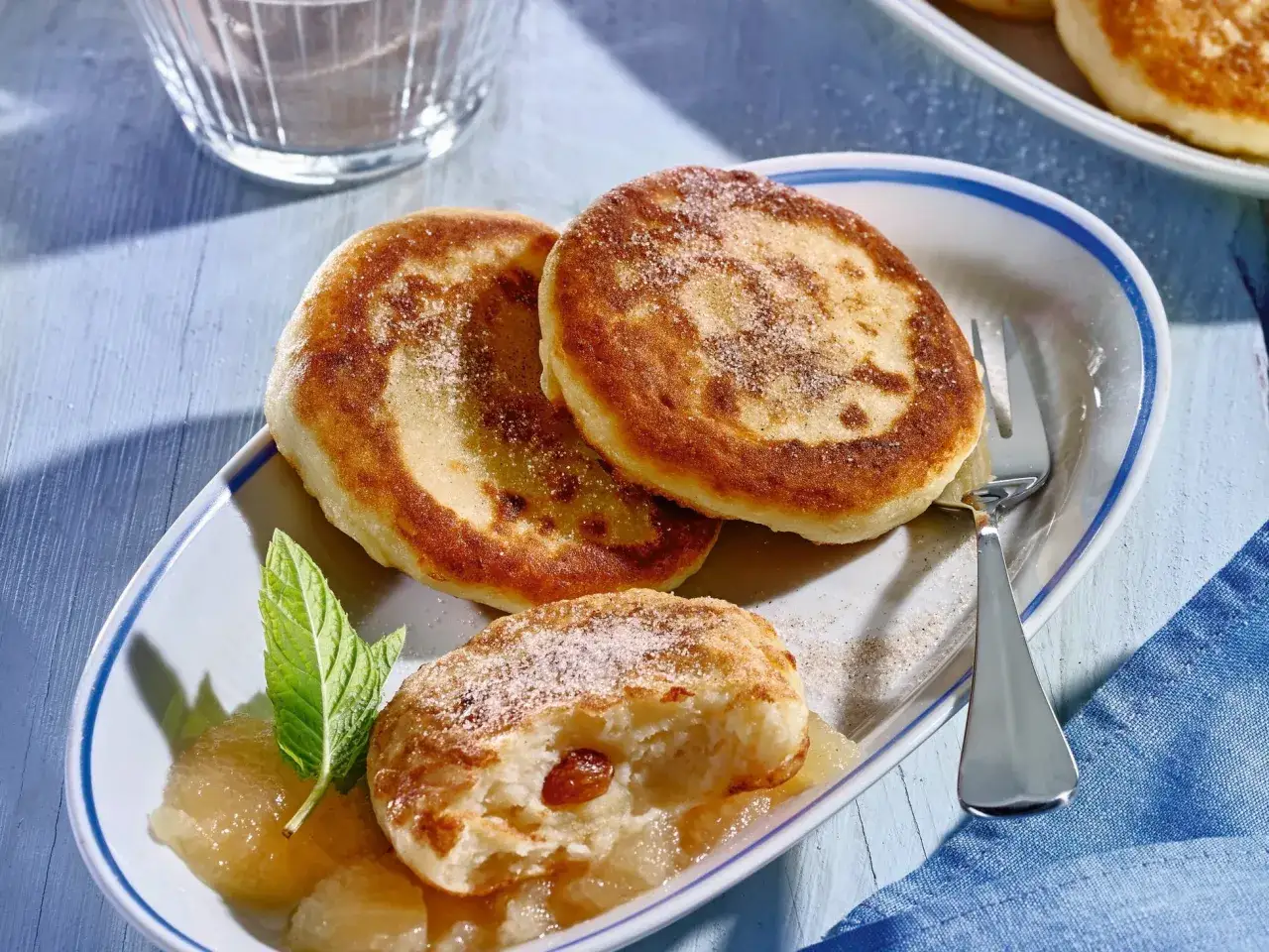 Goldbraune Quarkkeulchen mit Zucker bestreut, serviert mit Apfelmus und Minze. Ein leckeres Quarkkeulchen Rezept zum Genießen.