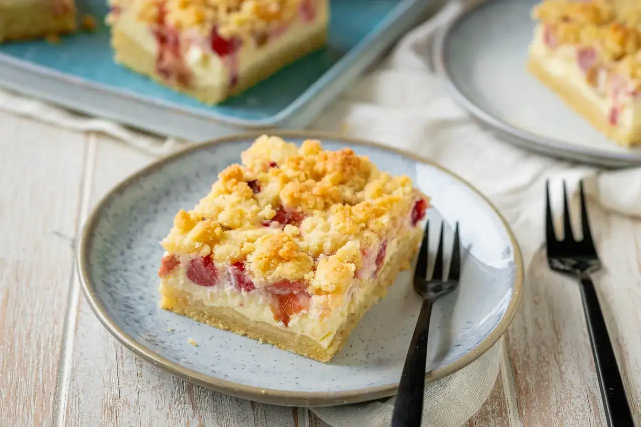Ein Stück von Omas Rhabarberkuchen mit Quark und Streuseln auf einem Teller, bereit zum Genießen.