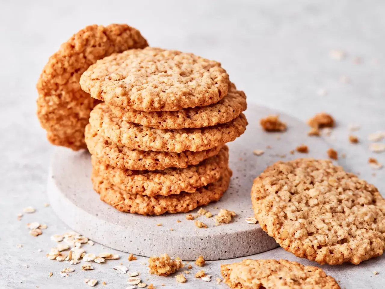 Ein Stapel goldbrauner Haferkekse, perfekt für ein schnelles Haferkekse Rezept. Krümel und Haferflocken liegen verstreut.