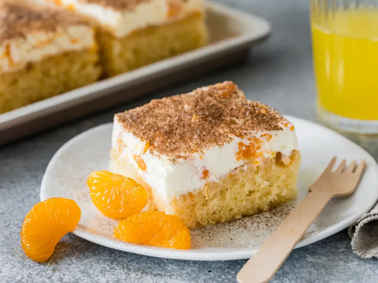 Ein saftiges Stück Fantakuchen mit Mandarinen und Sahne, bestreut mit Zimt. Ein tolles Fantakuchen Rezept für den Sommer!