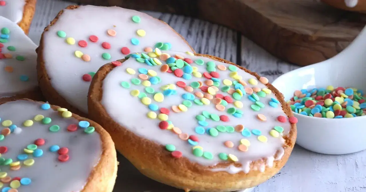 Amerikaner Rezept: Oval geformte Kekse mit weißer Glasur und bunten Streuseln. Perfekt für Kindergeburtstage!
