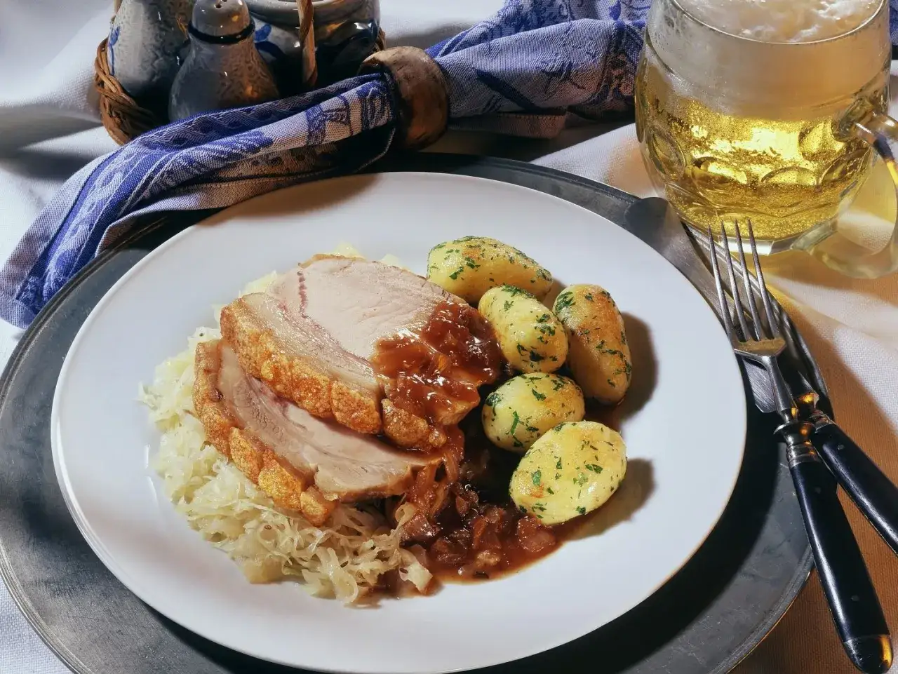Deftige dicke Rippe mit knuspriger Kruste, Sauerkraut, Klößen und einem kühlen Bier.