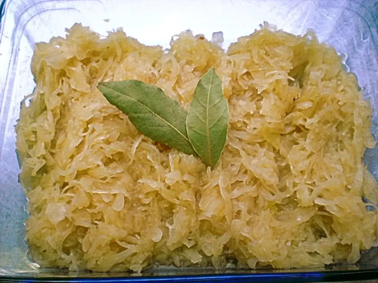 Sauerkraut kochen nach Omas Rezept: Ein Glas mit frisch gekochtem Sauerkraut, garniert mit zwei Lorbeerbl&auml;ttern.