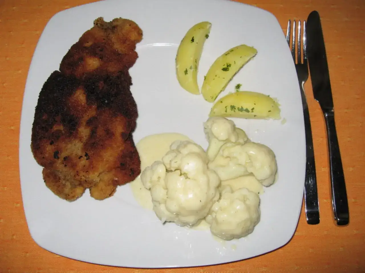Ein knuspriges Schnitzel mit cremiger Sauce, dazu Salzkartoffeln und Blumenkohl. Ein leckeres Blumenkohl-Schnitzel-Gericht.