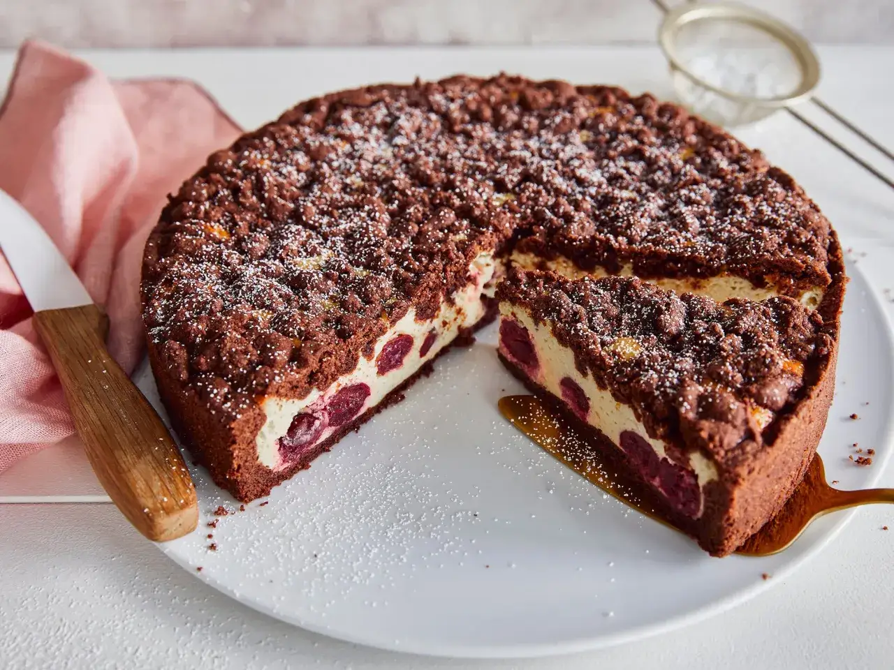 Ein saftiger, schneller Quark Kirsch-Kuchen mit Schokoladenstreuseln und vielen Kirschen, bestäubt mit Puderzucker.