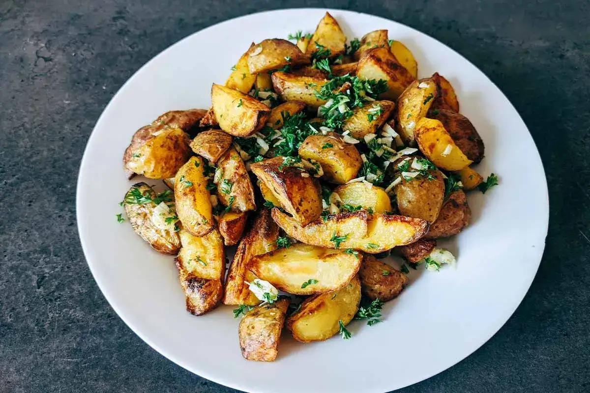 Goldbraun gegrillte Kartoffelspalten, garniert mit frischer Petersilie und Knoblauch. Perfekt vom Gasgrill!