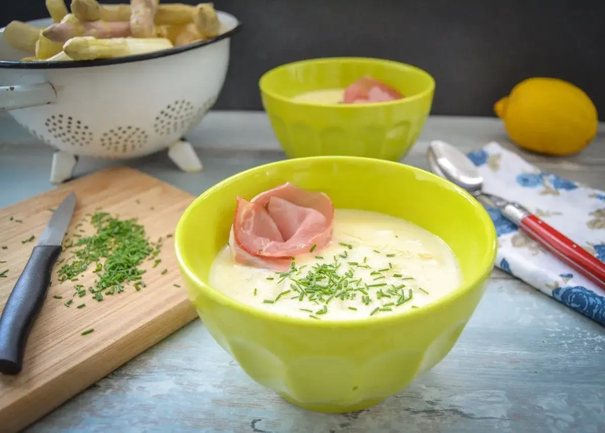 Spargelsuppe mit Schinkenröschen und Schnittlauch, zubereitet aus gekochten Spargelschalen.