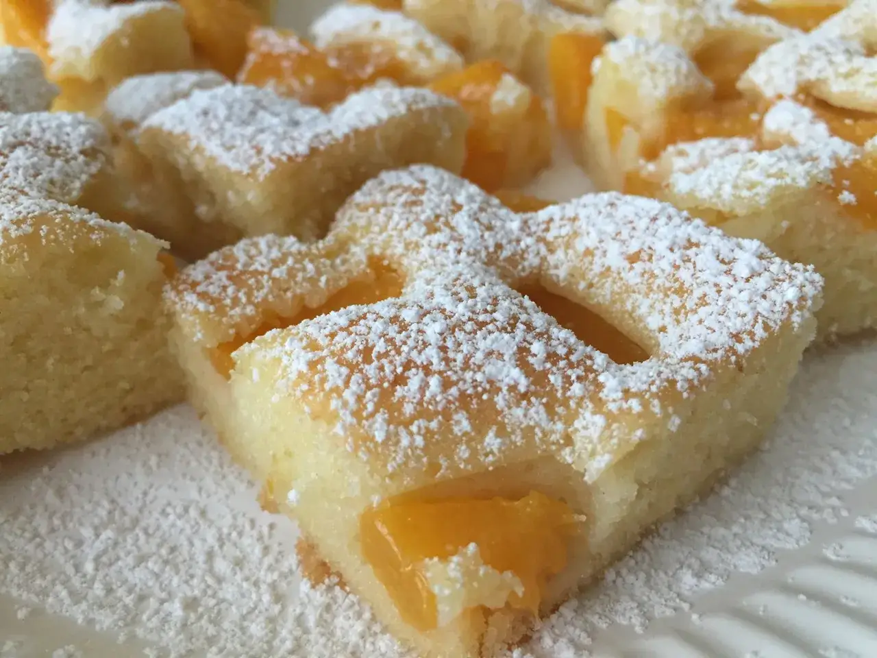 Saftiger Kuchen mit Pfirsichstücken, bestäubt mit Puderzucker. Ein süßer Genuss für jede Gelegenheit.