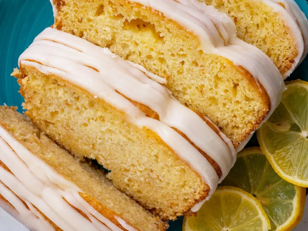 Saftiger zitronenkuchen mit Joghurt, überzogen mit süßer Glasur und garniert mit frischen Zitronenscheiben.