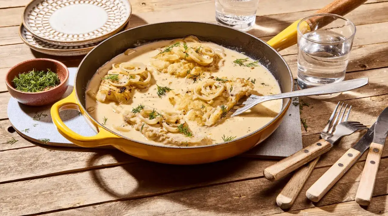 Gedünsteter Fisch in cremiger Sauce mit Zwiebelringen und Dill. Ein köstliches kochfisch rezept, bereit zum Servieren.
