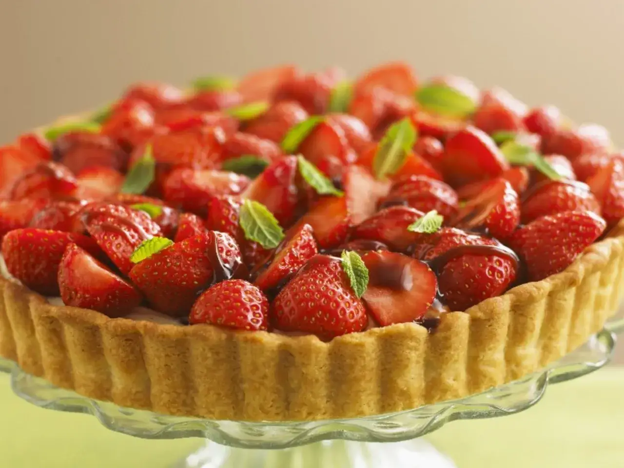 Ein köstlicher Erdbeerkuchen ohne Pudding, bedeckt mit frischen Erdbeeren und Minze, auf einem Glasständer.