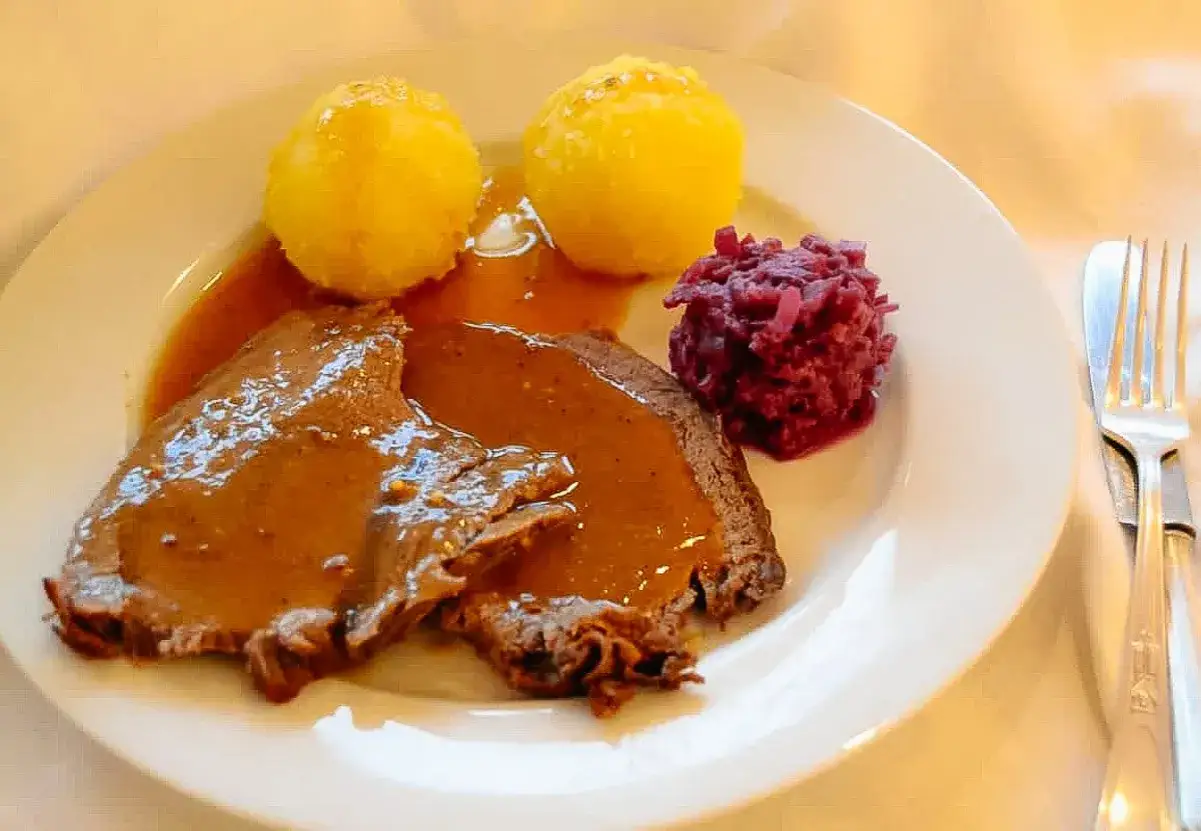 Zartes Fleisch in dunkler Soße, dazu Klöße und Rotkohl. Ein klassisches Sauerbraten Rezept, das man sich nicht entgehen lassen sollte.