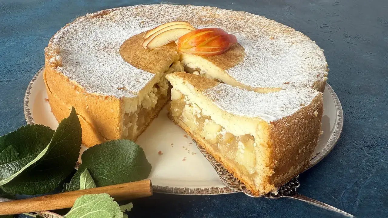 Saftiger apfelkuchen mit schmandguss, bestäubt mit Puderzucker und garniert mit Apfelscheiben. Ein Genuss für alle Sinne.