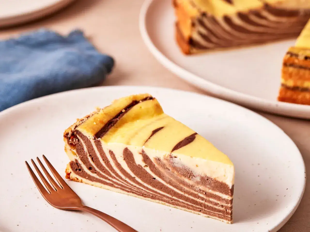 Ein Stück Zebrakuchen mit Quark, das auf einem Teller liegt, daneben eine Gabel.