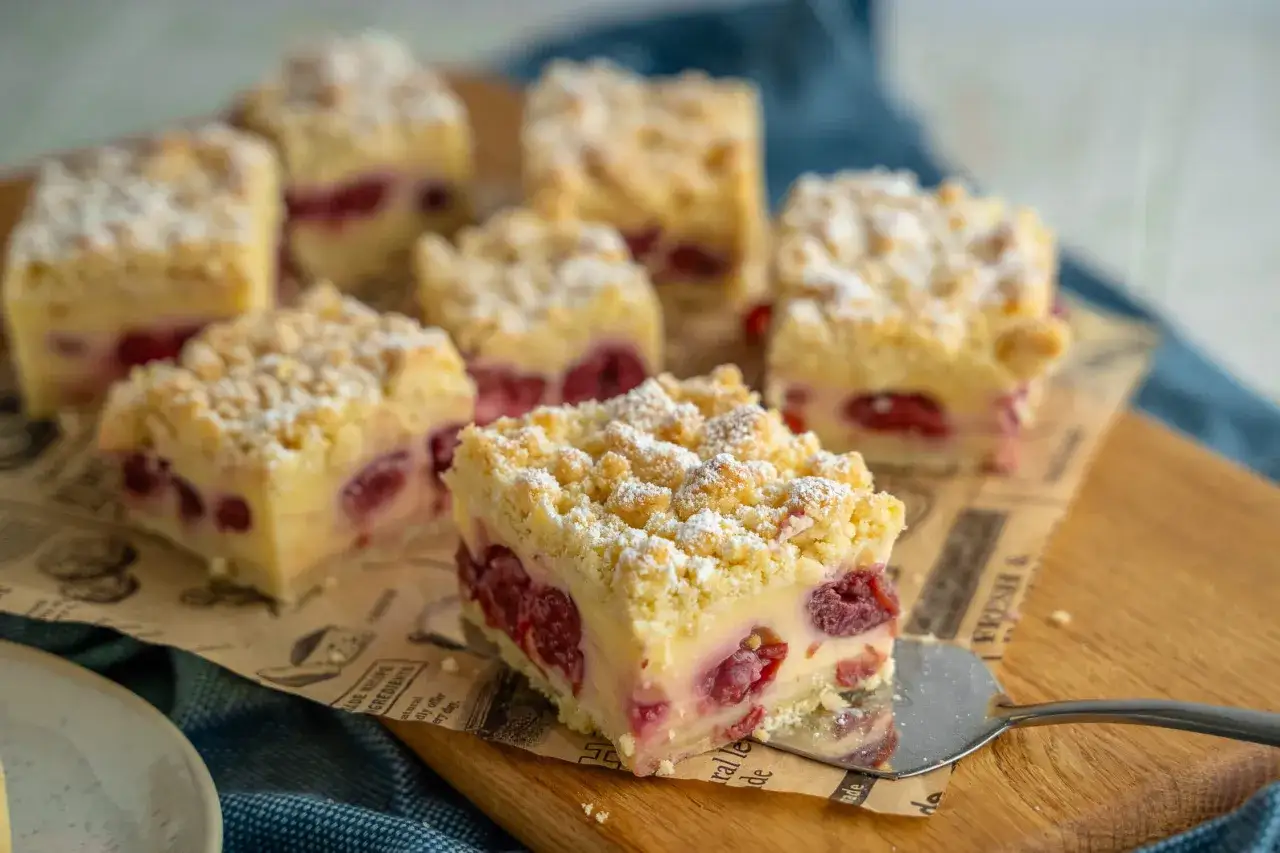 Saftiger Kirsch-Streuselkuchen, ein Klassiker unter den Blechkuchen-Rezepten, wird auf einem Holzbrett serviert.