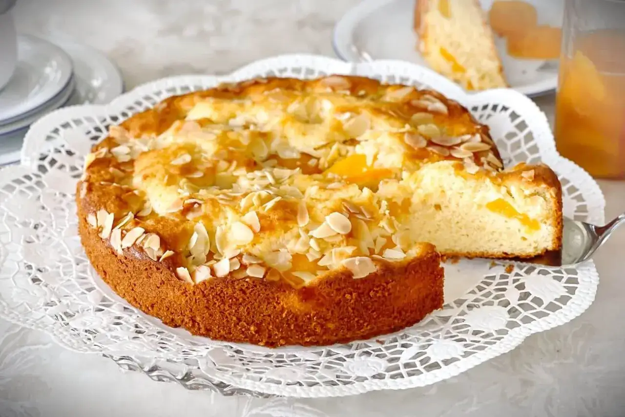Ein saftiger Landfrauen Aprikosenkuchen mit Mandelblättchen, frisch gebacken und bereit zum Genießen.