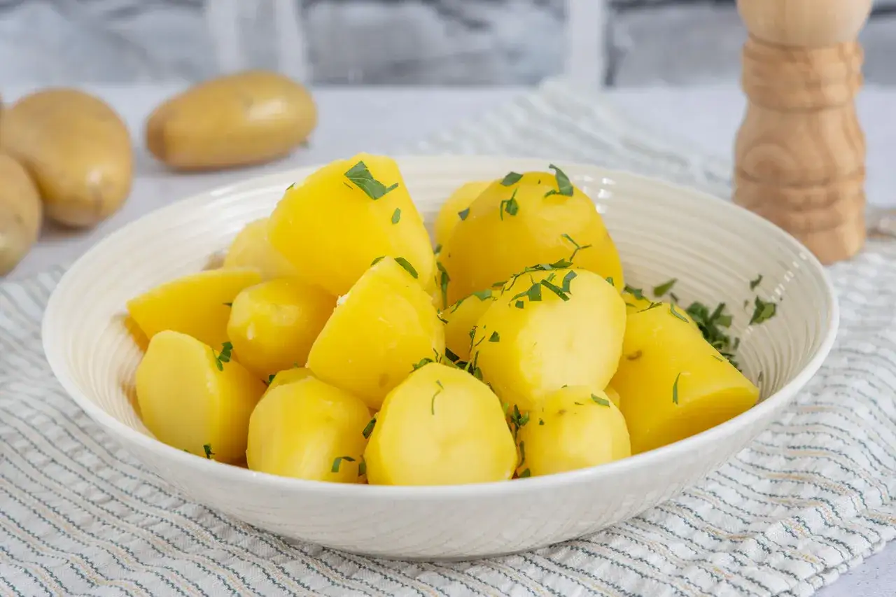 Schüssel mit dampfenden Salzkartoffeln, garniert mit Petersilie. Perfekt zum Kochen!