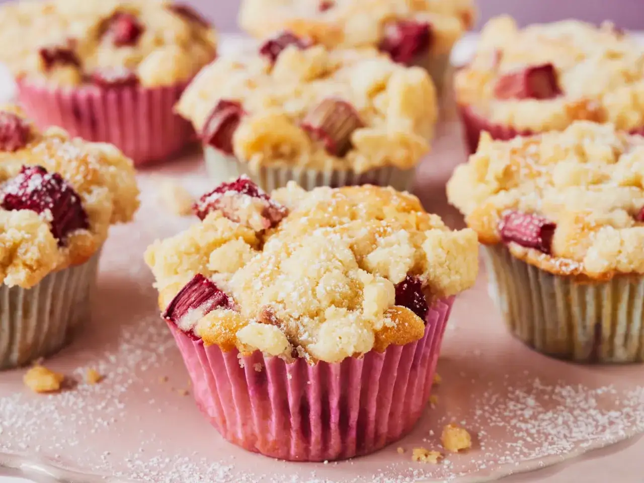 Saftige Rhabarber Muffins mit Streuseln, bestäubt mit Puderzucker. Ein süßer Genuss für den Nachmittagstee.