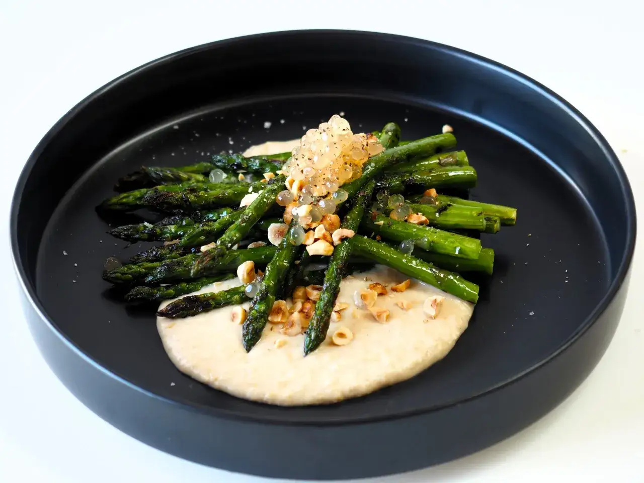 Gegrillter Spargel auf cremigem Bohnenmus, garniert mit Kaviar und Nüssen. Ein köstliches Rezept für Bohnenmus.