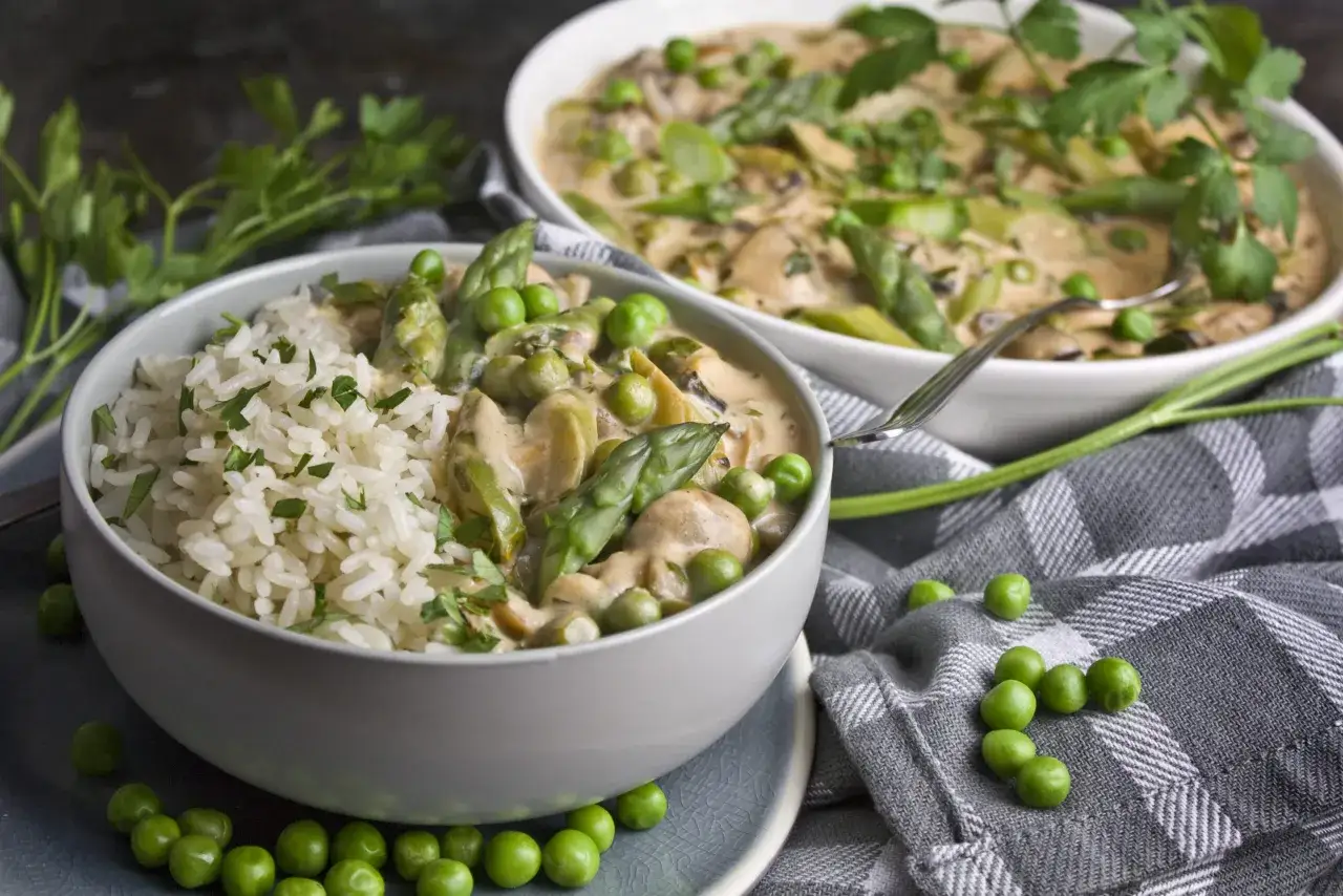 Cremige Champignons-Pfanne mit Spargel und Erbsen, serviert mit Reis. Ein köstliches Gericht, das Lust auf mehr Champignons Rezepte macht.