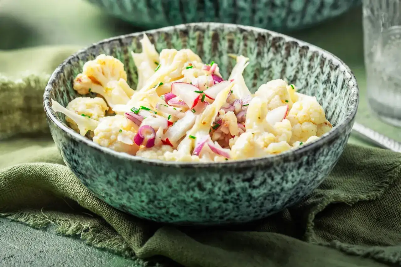 Ein köstlicher blumenkohl salat mit roten Zwiebeln und Kräutern in einer rustikalen Schüssel.