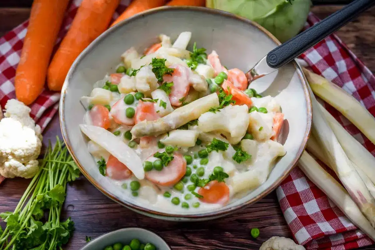 Leipziger Allerlei: cremiges Gemüse mit Spargel, Karotten, Erbsen und Blumenkohl, garniert mit Petersilie.
