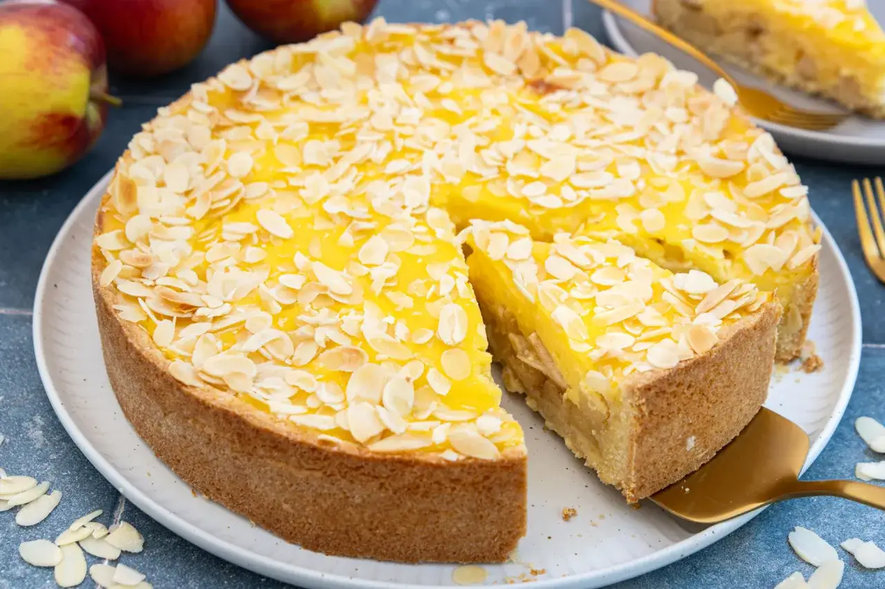 Ein köstlicher Apfelkuchen mit Mandelsplittern, perfekt für Ihr nächstes apfelkuchen rezept. Saftige Äpfel unter einer leuchtend gelben Decke.