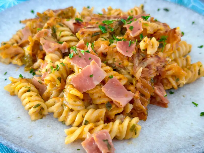 Nudel Schinken Gratin mit Käse überbacken, garniert mit Petersilie. Ein herzhaftes Gericht, das zum Genießen einlädt.